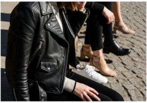 Kobieta w ramonesce i różnym obuwiu na bruku, naturalne światło, detal skóry i tekstur.